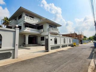 Spacious two-story house with a balcony and external stairs in a sunny suburban neighborhood