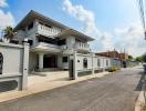 Spacious two-story house with a balcony and external stairs in a sunny suburban neighborhood