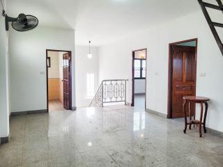 Spacious hallway with tiled flooring, wooden doors, and staircase