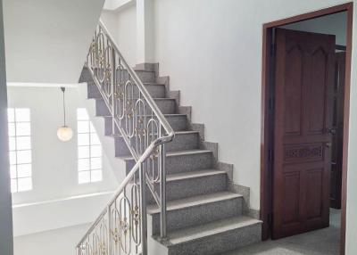 Bright staircase area with elegant metal railing, leading to the upper level of a home