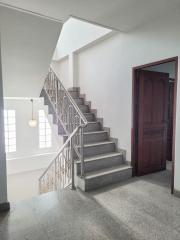 Bright staircase area with elegant metal railing, leading to the upper level of a home