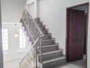 Bright staircase area with elegant metal railing, leading to the upper level of a home