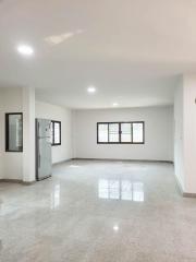 Spacious and bright empty interior of a property showing shiny tiled flooring and multiple windows