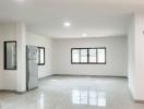 Spacious and bright empty interior of a property showing shiny tiled flooring and multiple windows