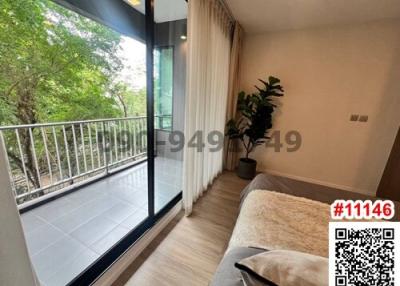 Cozy bedroom with balcony access, large window, and natural views