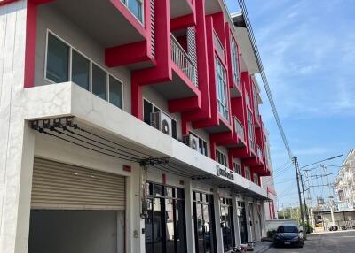 Modern commercial building with vibrant red accents and parking space