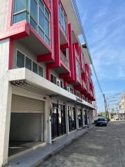 Modern commercial building with vibrant red accents and parking space