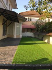 Exterior view of a residential house featuring a driveway and artificial lawn