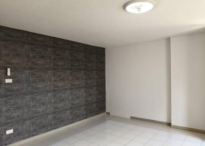 Spacious and empty room with tiled flooring and a dark-tiled accent wall