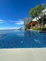 Infinity pool with ocean view adjacent to modern building