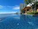 Infinity pool with ocean view adjacent to modern building