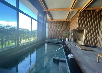 Modern indoor swimming pool with floor-to-ceiling windows and natural lighting