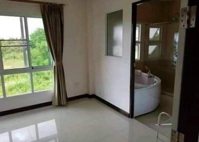 Spacious bedroom with a view of greenery and an adjoining bathroom with a bathtub