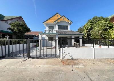 Two-story residential house with white fencing and clear blue skies