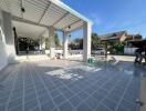 Spacious patio area with tiled flooring and partial roofing