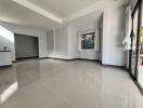 Spacious empty living space with glossy floor tiles and ample natural light