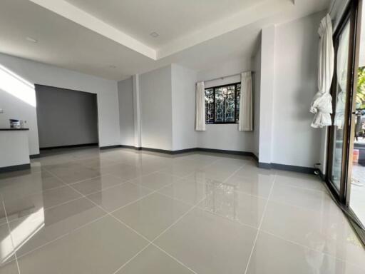 Spacious empty living space with glossy floor tiles and ample natural light