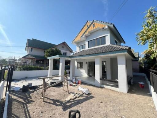 Exterior view of a two-story house under construction with materials scattered in the front yard