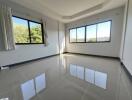 Spacious and bright empty living room with shiny tiled flooring and large windows