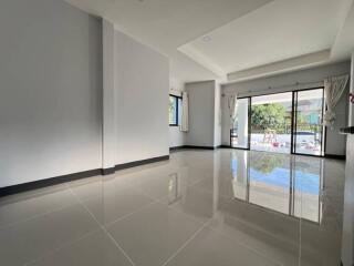 Spacious and well-lit living room with glossy floor tiles and large sliding glass doors