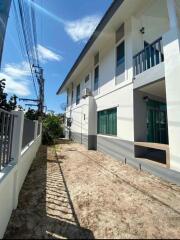 Exterior view of a modern two-story residential building with balcony and fenced yard