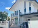 Modern two-story residential home with a balcony and gated entrance