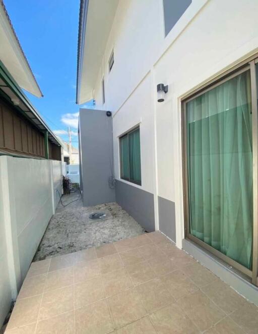 Side exterior view of a residential building showcasing windows and a narrow pathway