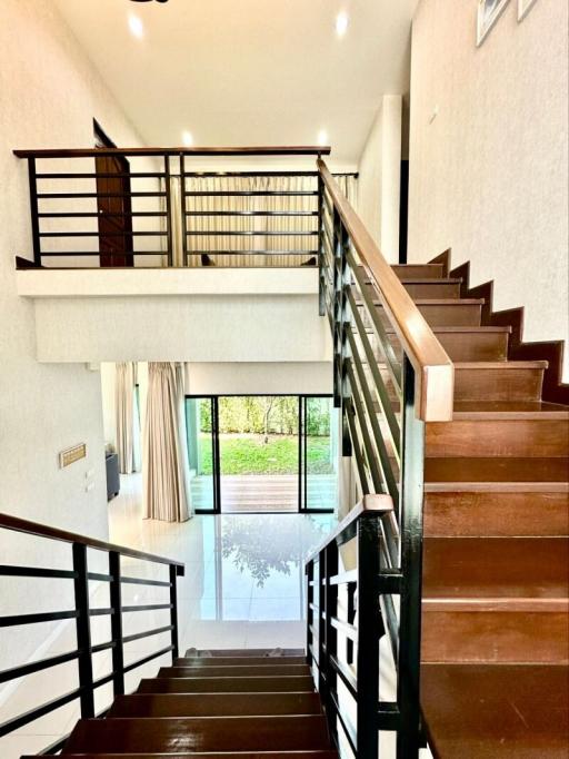 Bright and airy staircase leading to upper level with wooden steps and modern metal handrails