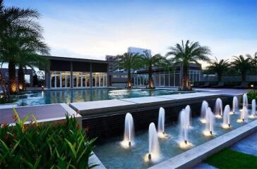 Luxurious resort-style building with illuminated fountains and pool area at dusk