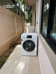 Outdoor laundry area with a modern washing machine beside a window