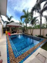Spacious backyard with a swimming pool and a gazebo amidst lush greenery