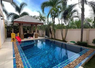 Spacious backyard with a swimming pool and a gazebo amidst lush greenery