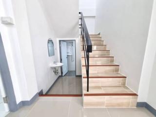 Modern staircase with wooden steps leading to the upper floor alongside a small bathroom