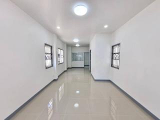 Brightly lit corridor with glossy tiled flooring and multiple doors