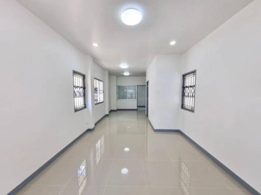 Brightly lit corridor with glossy tiled flooring and multiple doors