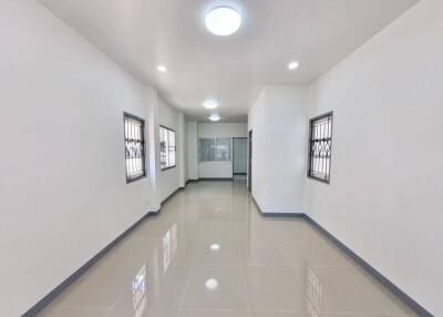 Brightly lit corridor with glossy tiled flooring and multiple doors
