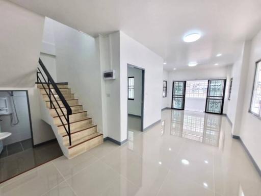 Spacious interior view of a building showcasing a staircase, bright living space, and multiple doors