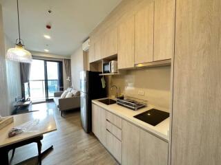 Modern kitchen with wooden cabinets and integrated appliances opening up to a cozy living room