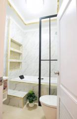 Modern bathroom interior with marble tiles and glass shower door