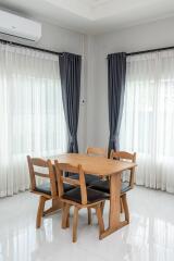 Modern dining room with a wooden table, chairs, and airy curtains