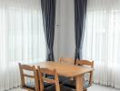 Modern dining room with a wooden table, chairs, and airy curtains