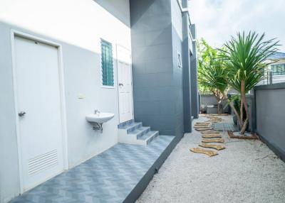 Exterior view of a modern home with outdoor sink and stepping stone pathway