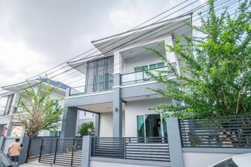 Modern two-story house with a sleek design and a gray color palette, featuring large windows and a secure fence