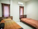Compact bedroom with twin beds and modern air conditioning unit