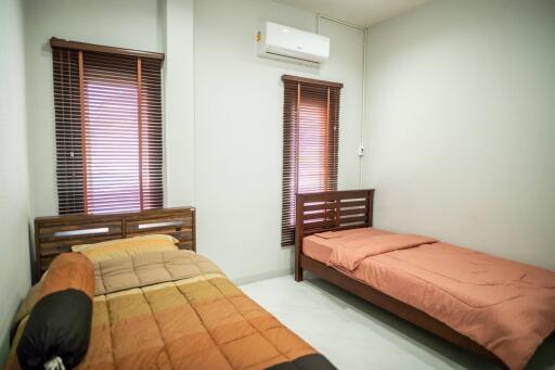 Compact bedroom with twin beds and modern air conditioning unit