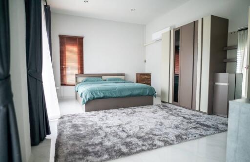 Spacious bedroom with modern design, queen-sized bed, and large windows