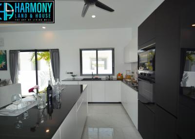 Modern kitchen with white countertops, integrated appliances, and open layout connecting to the dining area