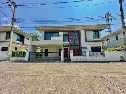 Modern two-story house with large windows and a fenced yard