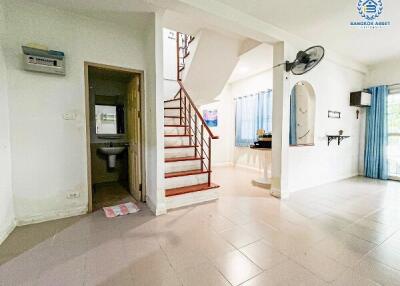 Spacious living area with staircase leading to upper floor and adjacent bathroom