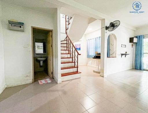 Spacious living area with staircase leading to upper floor and adjacent bathroom